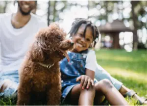 Dad, daughter and dog outside at park looking happy